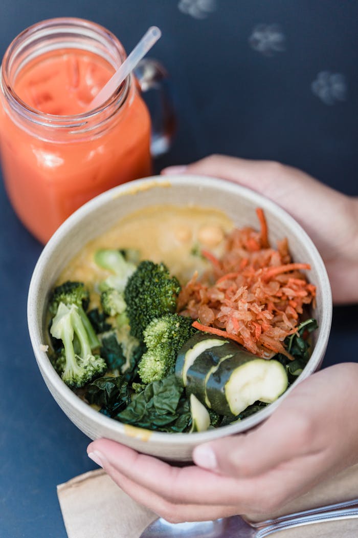 Crop person with bowl of tasty vegetable salad in cafe